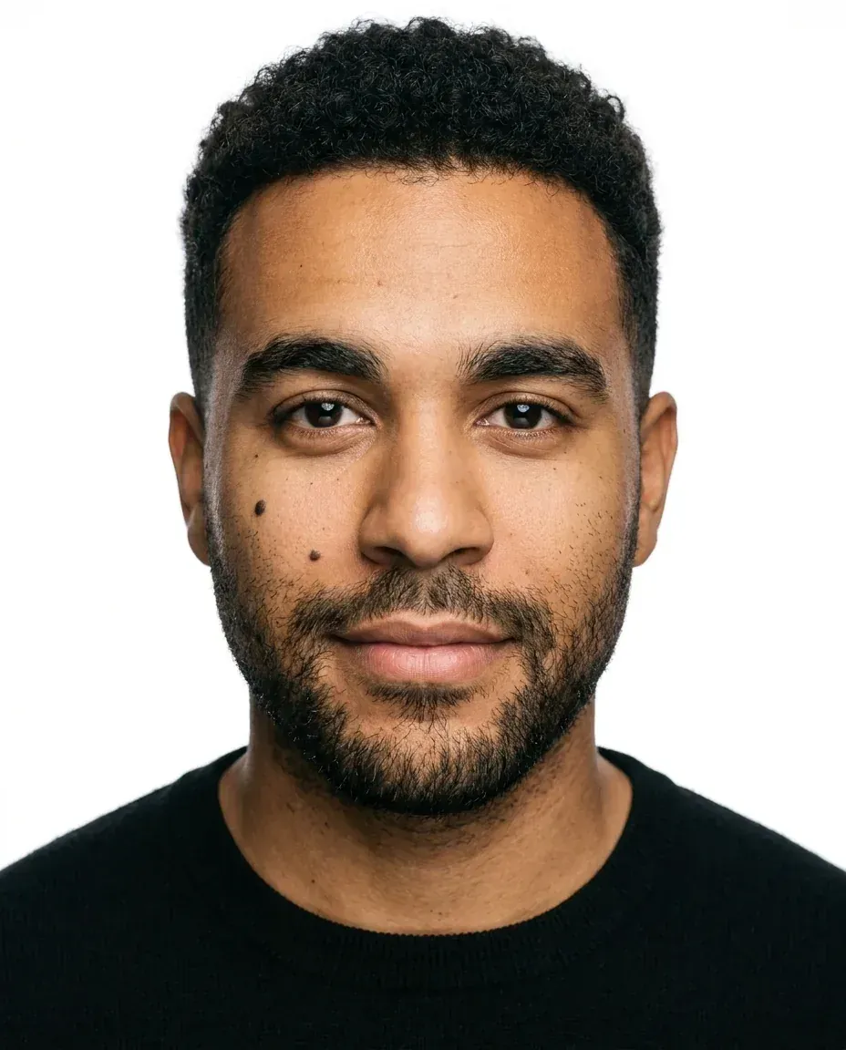 Studio headshot of the same man in a black sweater on a pure white background with butterfly lighting